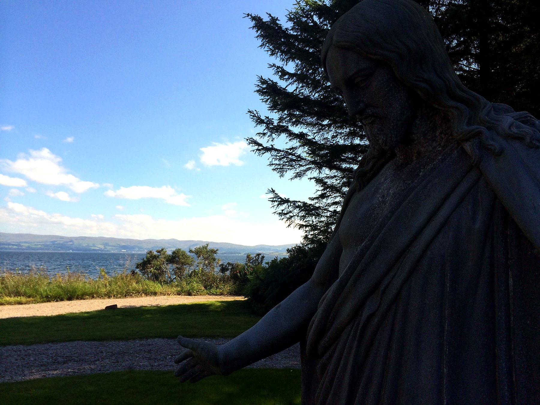 Stone statue of Christ with arms outstretched above the Firth of Clyde on the Mount Stuart estate, Isle of Bute