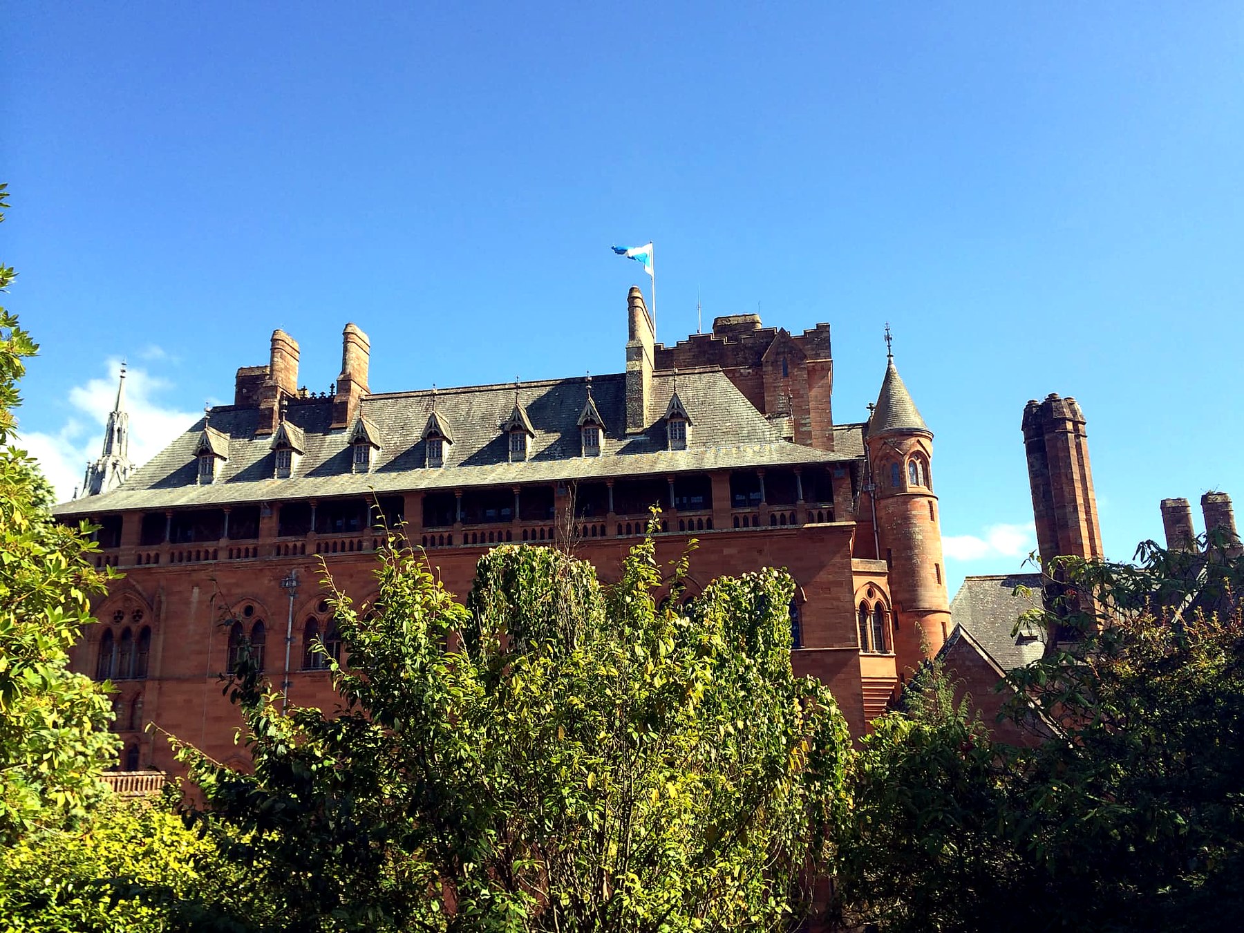 The red sandstone roofline and Saltire flag of Mount Stuart House on the Isle of Bute