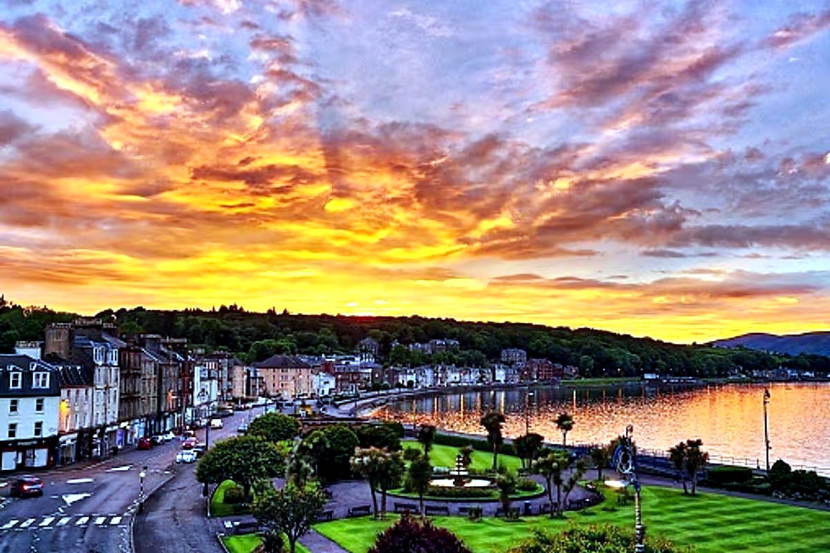 A vivid sunset over Rothesay Bay, with the Victorian seafront and the hills of Bute silhouetted against orange and pink skies